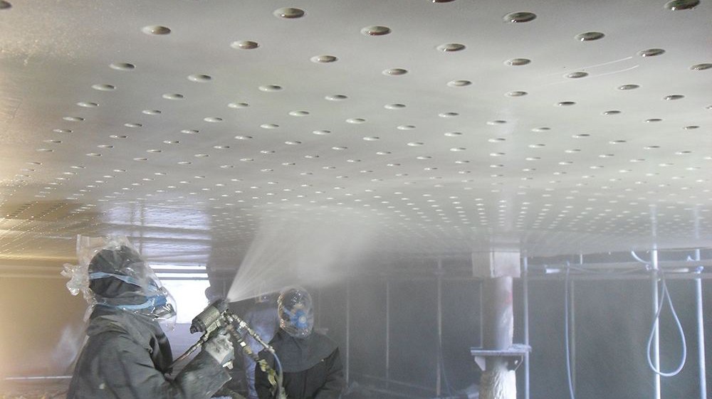 Workers applying spray polyurea coating inside desalination caisson for marine anti-corrosion protection