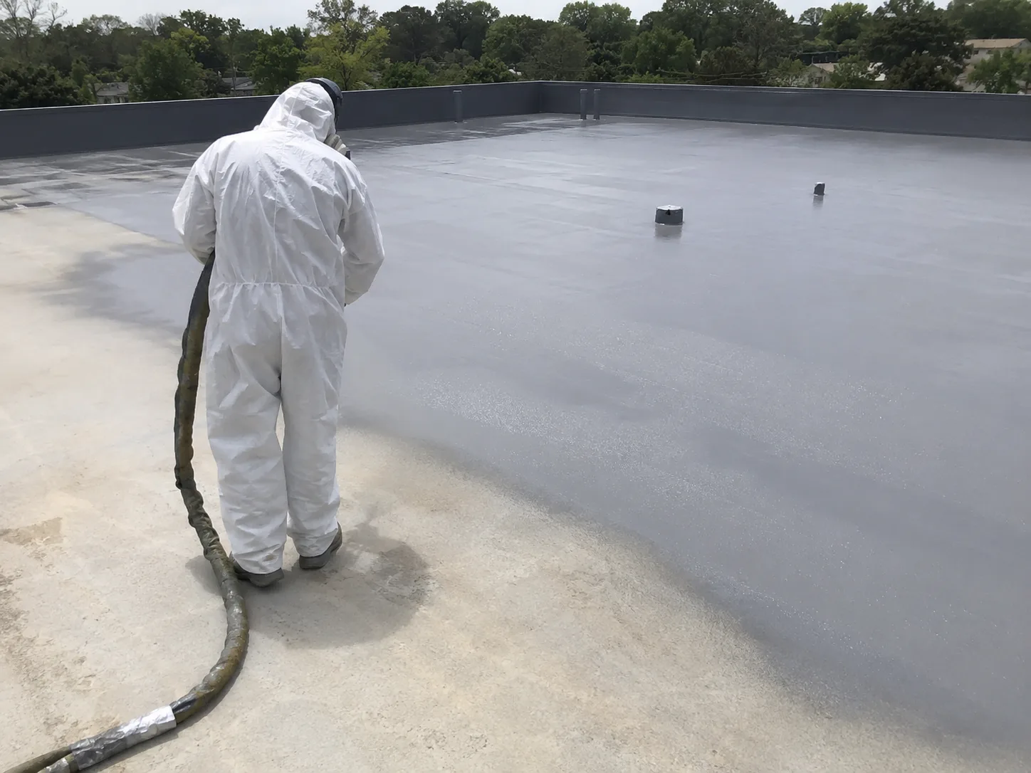 Spray polyurea application on a concrete roof waterproofing project with a grey seamless membrane