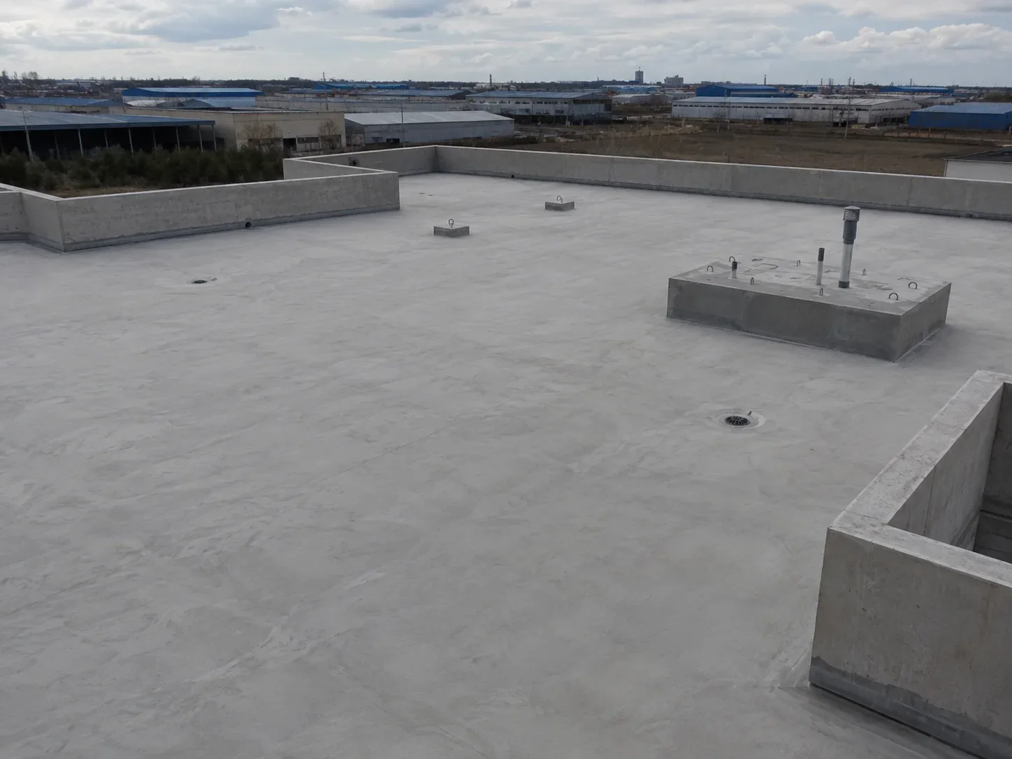Spray polyurea concrete roof waterproofing construction progress on an industrial flat roof before primer application