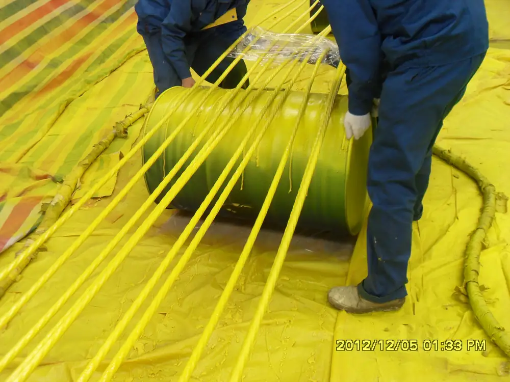 Workers handling coated bridge steel strands after spray polyurea application