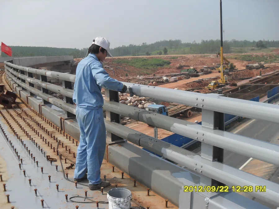 Close-up of worker coating bridge railing connection detail