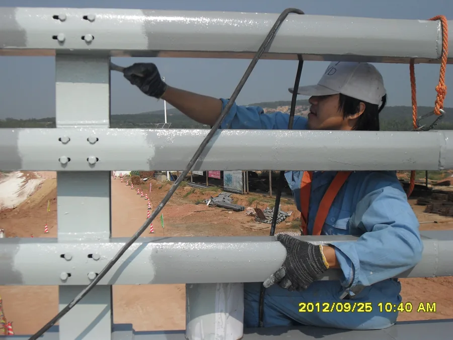 Close-up of bridge railing bolts and weld areas during protective coating