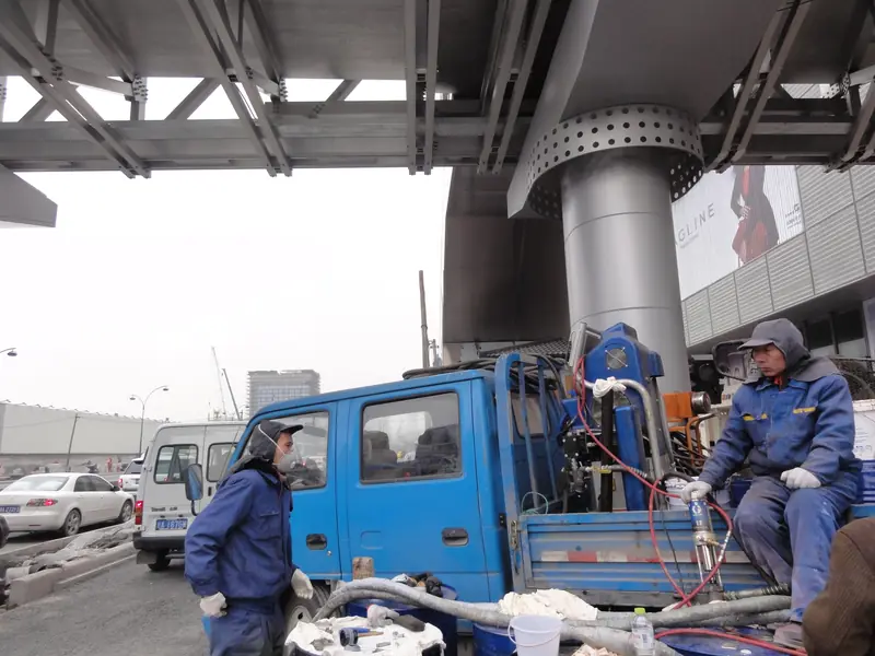 Spray coating equipment beside pedestrian overpass steel support structure