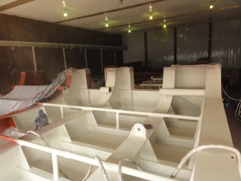 Worker applying protective coating around ship internal ribs and stiffeners
